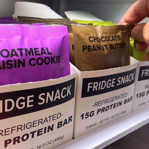 Close-up of Fridge Snack protein bars in a refrigerator, featuring Oatmeal Raisin Cookie and Chocolate Peanut Butter flavors